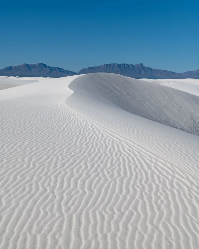 Serene white gypsum dunes under a clear blue sky at White Sands National Park, New Mexico.