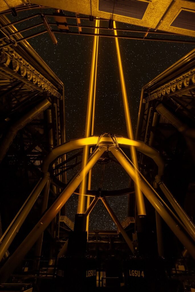 A large telescope firing laser guide stars into the night sky